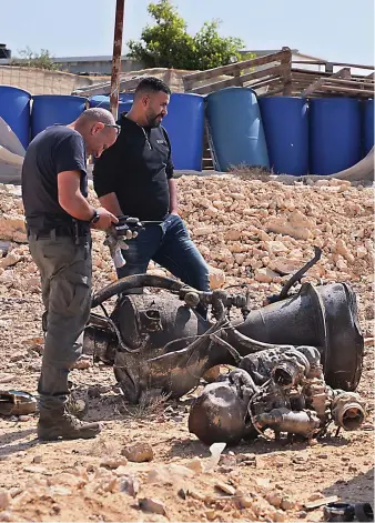 ?? Reuters ?? A police officer inspects the remains of a rocket booster on Sunday near Arad, Israel. The rocket critically injured a seven-year-old girl, Israeli authoritie­s said after Iranian forces launched drones and missiles toward Israel.