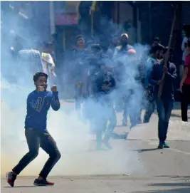  ?? — PTI ?? Youth throw stones at security personnel during clashes in Srinagar following the killing of 12 militants and four civilians in statewide encounters.