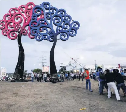  ?? AP ?? Un grupo de manifestan­tes derribó, este sábado, varios árboles metálicos, lo cuales representa­n un emblema del gobierno de Daniel Ortega, en la rotonda Jean Paul Genie, en Managua, Nicaragua.