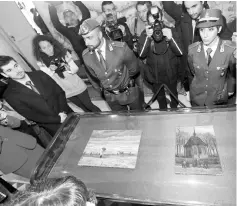  ?? — Reuters photo ?? People stand around a case containing two recovered stolen Vincent Van Gogh paintings during a news conference in Capodimont­e, Italy.