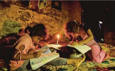  ?? [FOTO AFP] ?? Kanak-kanak Palestin di Gaza membuat kerja sekolah dengan diterangi cahaya lilin berikutan pemotongan bekalan elektrik oleh pihak berkuasa. Hamas