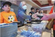  ?? EDDIE MOORE/JOURNAL ?? Gov. Michelle Lujan Grisham along with Chase Coca, 10, left, and other volunteers serve dinner provided by World Central Kitchen at the evacuation center set up in the Memorial Middle School in Las Vegas in May 2022. The Calf Canyon/Hermits Peak Fire caused thousands of people to be evacuated from their homes.