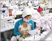  ?? PHA LINA ?? Garment factory workers sit at work stations and sew clothing for export at a factory in Phnom Penh’s Sen Sok district.