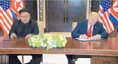  ?? EVAN VUCCI/ASSOCIATED PRESS ?? President Donald Trump signs an agreement with North Korean leader Kim Jong Un after their meeting in Singapore on Tuesday.