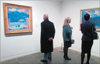  ?? BETH J. HARPAZ/AP PHOTO ?? Visitors look at paintings from the “Marsden Hartley’s Maine” show at The Met Breuer Museum in New York on March 20. Maine’s tourism agency has created itinerarie­s that match the artwork for travelers who’d like to visit the places depicted in the...
