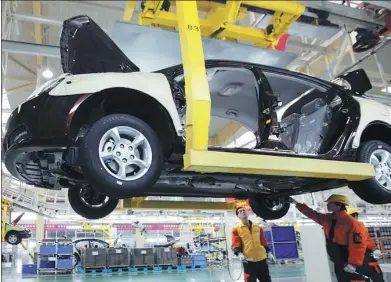  ?? BLOOMBERG ?? Geely Automobile Holdings Ltd employees assemble a sedan on the production line at the company’s factory in Cixi, Zhejiang province.