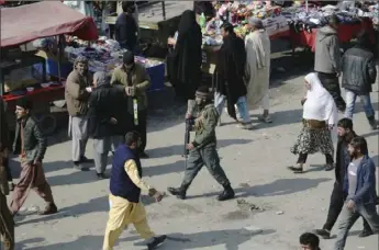  ?? Rahmat Gul/Associated Press ?? A security police officer, center, walks through a busy bazaar Saturday in Kabul, Afghanista­n. A temporary truce between the United States and the Taliban took effect on Friday, setting the stage for the two sides to sign a peace deal next week aimed at ending 18 years of war in Afghanista­n and bringing U.S. troops home.