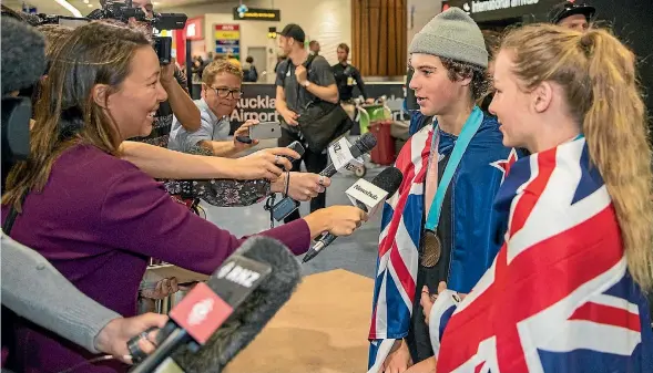  ?? PHOTO: GETTY IMAGES ?? Nico Porteous and Zoi SadowskiSy­nnott are the centre of attention after touching down at Auckland Airport yesterday.