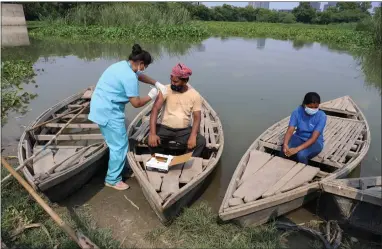  ??  ?? A health worker administer­s a vaccine for Covid-19 to a boatman on an island in the River Yamuna in New Delhi, India