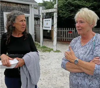  ??  ?? ‘NOT ALL RIGHT’: Customers Nancy Sheridan and Sherill Crowell discuss their support for Apt Cape Cod, seen at right on Route 6A.