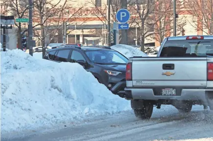  ?? MICHAEL SEARS / MILWAUKEE JOURNAL SENTINEL ?? Snow piles block the line of sight for a driver at a parking lot in the 300 block of West Kilbourn Avenue.