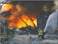  ??  ?? Firefighte­rs douse a blaze at the scene of an explosion at the port of Lebanon’s capital Beirut Tuesday. Right, a helicopter tries to put out the flames.