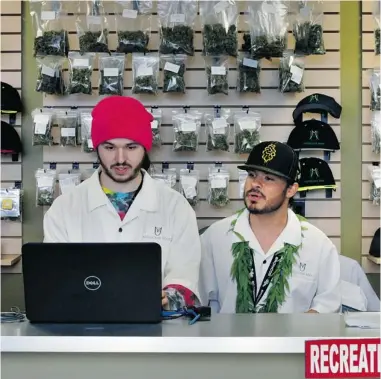  ?? BRENNAN LINSLEY/ THE ASSOCIATED PRESS FILES ?? Chris Broussard, left, and David Marlow work behind the sales counter at the Medicine Man marijuana retail store in Denver. Colorado made roughly $ 2 million in marijuana taxes in January, state revenue offi cials reported this week.