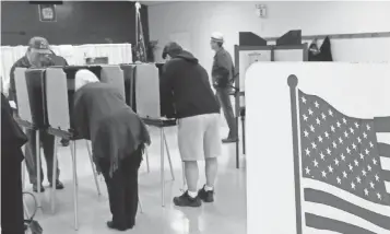  ?? SETH PERLMAN, AP ?? People cast their ballots for the midterm elections Nov. 4, 2014, in Springfiel­d, Ill. An unidentifi­ed hacker gained access to the state’s voter registrati­on database.