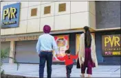  ??  ?? A couple with a child walks in front of a closed PVR cinemas, in Amritsar, on Sunday
