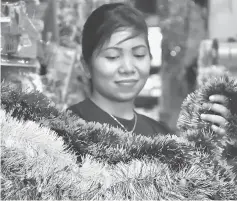  ??  ?? A shopkeeper arranges Christmas decoration­s for sale.