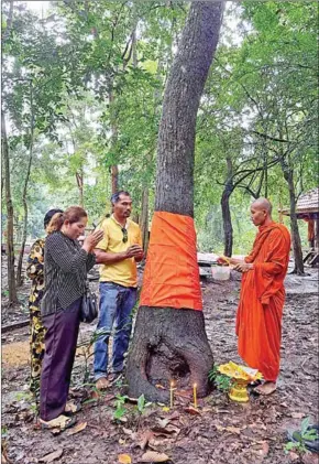  ?? MCF ?? Bunthoeun (in yellow T-shirt) and his wife (left) attend a tree ordaining ceremony in July at the Sorng Rukhavorn community forest in Oddar Meanchey province.