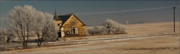  ?? Paul Davenport/AP ?? Sights: A decrepit but still eye-catching old building, possibly a church or schoolhous­e, on the far side of a two-lane road is glimpsed from Amtrak's Empire Builder in the North Dakota countrysid­e.