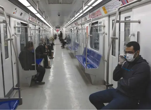  ?? (Ali Khara/WANA via Reuters) ?? PEOPLE WEAR protective face masks, following the outbreak of coronaviru­s, as they sit in a metro in Tehran.