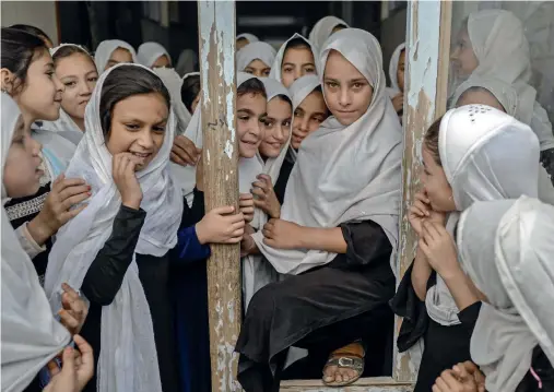  ?? AFP ?? Afghan girls step out of their classes in a school in Kandahar on Monday. Girls are allowed to go to primary school but have been excluded from secondary school . Women studying at private universiti­es can return to single-sex classrooms with strict rules imposed on attire. —