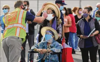  ?? GETTY IMAGES/TNS ?? In a parking lot at Disneyland, people receive temperatur­e checks Jan. 13 as they wait to receive the COVID-19 vaccine at the mass vaccinatio­n site in Anaheim, California.