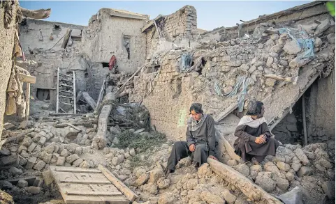  ?? NYT ?? Two brothers sit outside their family home, which was heavily damaged by the earthquake which stuck Gayan district last week.