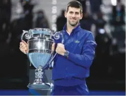  ?? Reuters ?? ↑
Novak Djokovic celebrates with the trophy for his 2021 world number one ranking after winning his group stage match against Casper Ruud.