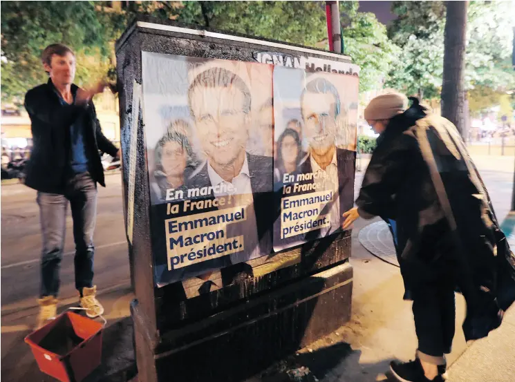  ?? JACQUES DEMARTHON / AFP / GETTY IMAGES ?? Supporters put up posters for French presidenti­al election candidate Emmanuel Macron on Friday in Paris.