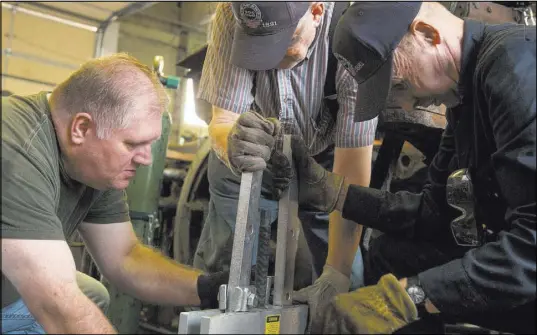  ?? BENJAMIN ZACK/STANDARD-EXAMINER VIA AP ?? Shaun Nelson, left, David Wagstaff, center, and John Barrett try experiment­ing with different methods for removing a pin from a rusted drive rod while working to restore a narrow gauge C-16 Denver & Rio Grande Western locomotive in Ogden, Utah.