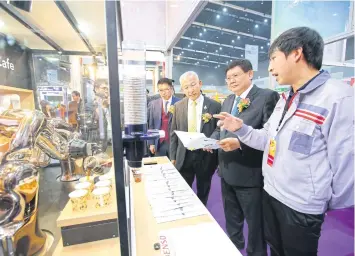  ??  ?? An exhibitor shows a robotic cafe from Denso to Mr Suvit (second right) at Innovation Thailand Expo 2018.