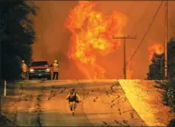  ?? DAVID MCNEW / AGEANCE FRANCE-PRESSE ?? Flames rise as a fire front approaches the Lake Casitas area on Friday near Ojai, California. Strong Santa Ana winds have been feeding major wildfires all week, destroying hundreds of houses and forcing tens of thousands of people to stay away from...