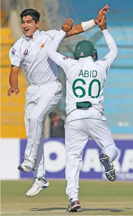  ?? (AFP) ?? Pakistan's Naseem Shah (left) celebrates with teammate Abid Ali after taking the wicket of Sri Lanka's Lasith Embuldeniy­a (not in photo) during the second Test at the National Cricket Stadium in Karachi on Monday