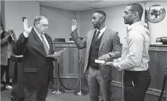  ?? Jerry Baker / For the Chronicle ?? State Representa­tive Cecil Bell, from left, swears in new Prairie View Councilman Xante Wallace, 21, with Xante’s dad, Jeffrey, holding the Bible, at Prairie View City Hall on June 5.