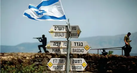  ??  ?? Un soldato israeliano accanto ai cartelli che indicano le distanze da diverse città, sul Monte Bental, posto di osservazio­ne sulle alture del Golan occupate da Israele