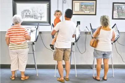  ?? STAFF PHOTO BY DOUG STRICKLAND ?? Trace Brewington watches from the arms of his uncle, Mike Summers, as Summers votes at the Chickamaug­a Civic Center on Tuesday. Turnout was steady at the polling place for Georgia’s Tuesday primary election.