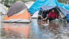  ??  ?? A Central American migrant looks on from inside her tent while camping near a closed temporary shelter a few metres from the Us-mexico border. — AFP