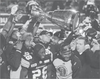  ?? CP PHOTO ?? Toronto Argonauts head coach Marc Trestman, centre, and players celebrate with the Grey Cup after defeating the Calgary Stampeders in the 105th Grey Cup.
