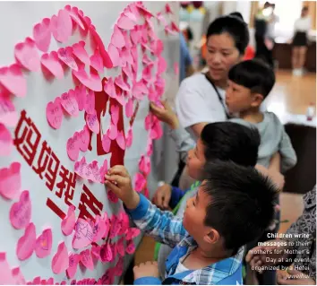  ??  ?? Children write messages to their mothers for Mother's Day at an event organized by a Hefei juweihui