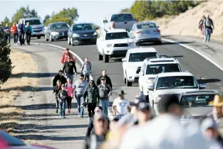  ?? PHOTOS BY LUIS SÁNCHEZ SATURNO/THE NEW MEXICAN ?? ABOVE: Pilgrims walk to El Santuario de Chimayó on Good Friday. TOP: A Virgin Mary statue greets people as they arrive Friday morning at the santuario.