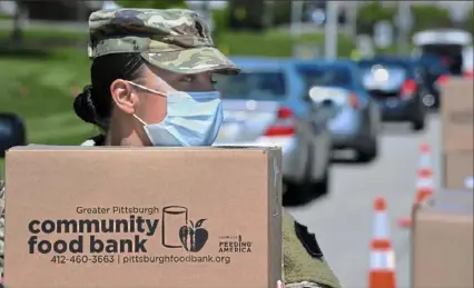  ?? Darrell Sapp/Post-Gazette ?? Specialist Niki Myers, of the 128th Brigade Support Battalion of the U.S. Army in Pittsburgh, waits Monday for a vehicle to pull up for food in Duquesne.