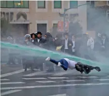  ??  ?? A bystander falls as Israeli police spray water cannons during a demonstrat­ion by ultra-Orthodox Jews against the detention of members of their community who failed to report to a military recruiting office in Jerusalem