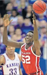  ??  ?? Oklahoma forward Kur Kuath, right, reaches for a loose ball during Saturday's game against Kansas in Lawrence, Kan. [AP PHOTO/ORLIN WAGNER]