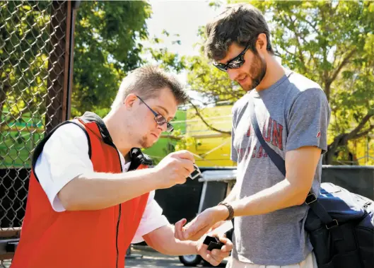  ?? Connor Radnovich / The Chronicle ?? Champ Pederson stamps the wrist of Ken Fockele at a men’s soccer game this month at Stanford, where Champ works as an usher at sporting events.