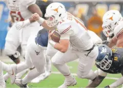  ??  ?? Texas quarterbac­k Sam Ehlinger is on the run Saturday against West Virginia. The Longhorns clinched their first bowl berth since 2014 in the victory.
| AP