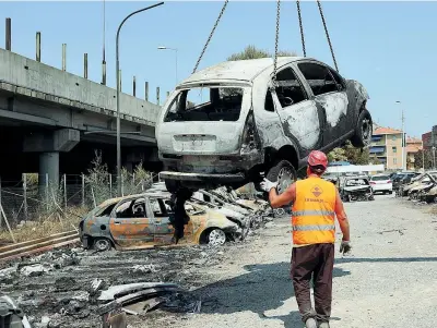  ??  ?? Distrutte Una gru solleva i resti di una delle automobili distrutte dall’esplosione del Tir cisterna in autostrada