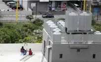  ??  ?? Two men smoke a water pipe as they sit on the rooftop of their building.