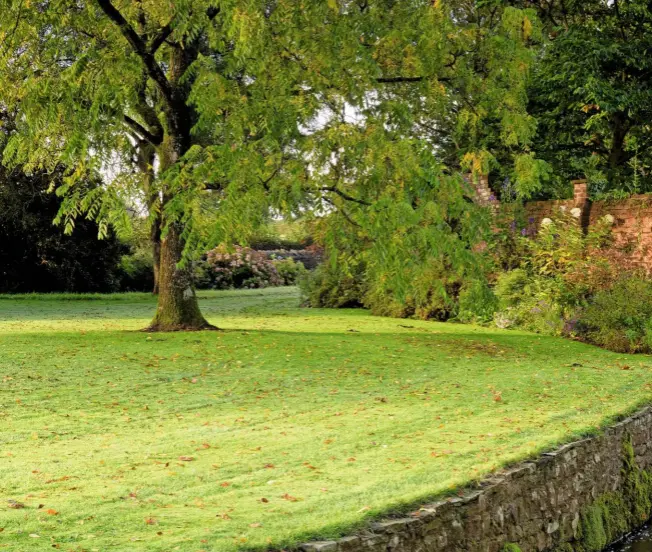  ??  ?? Water runs along a stone-lined channel snaking across the lawns after emerging through an archway and under a simple crossing point.