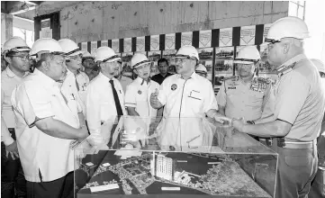  ??  ?? Hishammudd­in (third right) sharing his view as he takes a closer look at the Malaysian Armed Forces’ Wisma Bintara Complex model during his visit. — Bernama photo