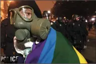  ?? KEVIN G. HALL/MCCLATCHY ?? A protester with a gas mask checks her surroundin­gs as police move crowds back at nightfall in downtown Washington, D.C., on Friday.