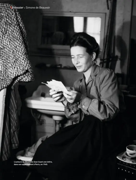  ??  ?? L’auteure du Deuxième Sexe lisant une lettre, dans son appartemen­t à Paris, en 1945.